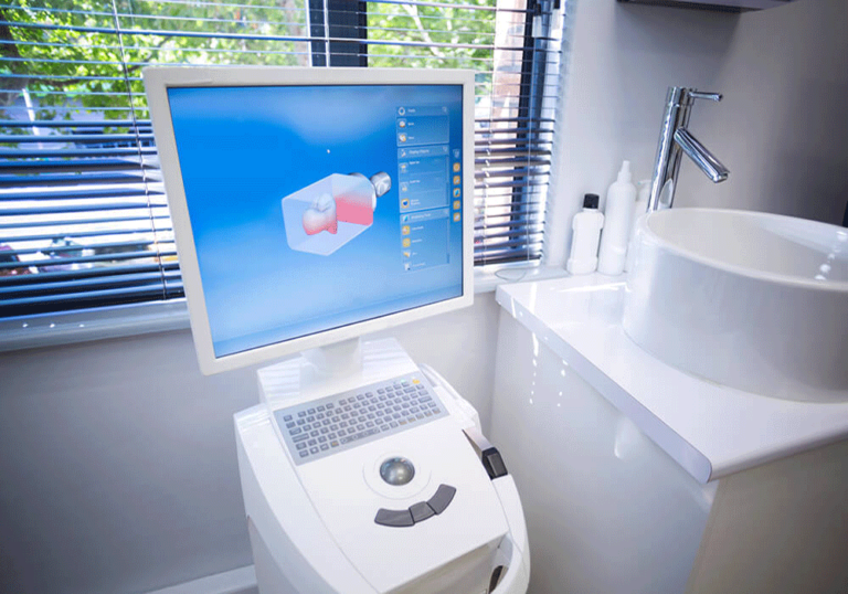 A dental CAD/CAM (computer-aided design and computer-aided manufacturing) system in a dental office. The setup includes a computer with a monitor displaying a 3D model of a dental restoration and a milling machine used to fabricate the dental restoration based on the digital design.