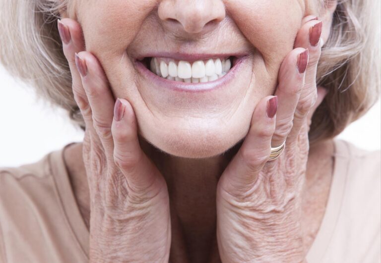 Woman smiling while touching her cheeks representing relief from dental pain.