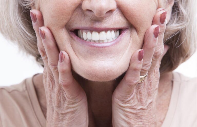 Woman smiling while touching her cheeks representing relief from dental pain.