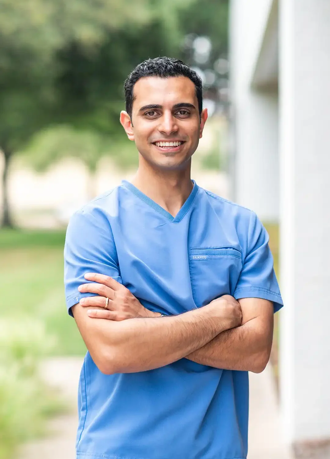 Portrait of a smiling dentist in blue scrubs representing Covenant Dental.