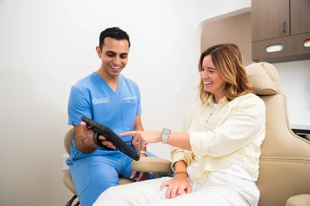 Patient reviewing digital dental treatment information with a dentist on a tablet during a consultation.